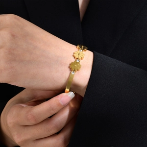 Gros plan d'un bracelet fleuri doré avec zircons brillants porté par un mannequin
