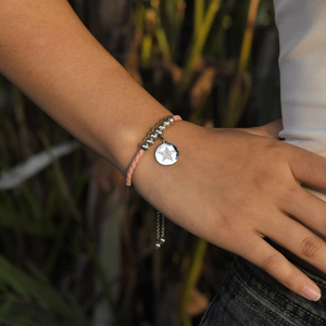 Pink braided leather bracelet with star pendant and silver beads on a woman wrist