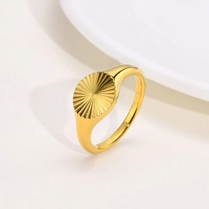 Macro view of gold stainless steel ring with radial sunburst texture and polished finish
