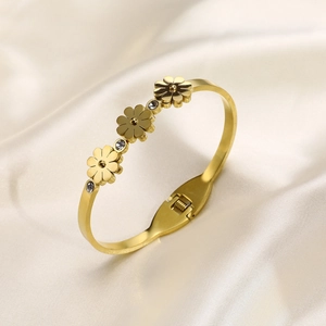 Détail d'un bracelet floral doré avec trois fleurs et zircons sur soie beige