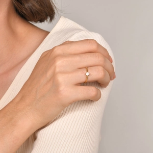 Close-up of elegant gold ring with a single white zircon worn on a woman's finger