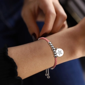 Detail of adjustable pink braided rope bracelet with silver star pendant and zircon stones