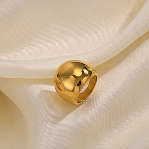 Detailed macro view of gold polished domed ring on soft cream silk fabric