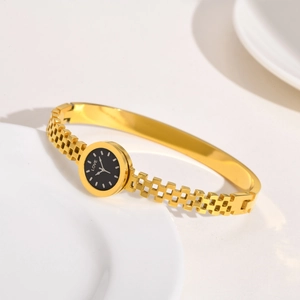 Gros plan d'une montre bracelet dorée avec cadran noir et gravure chiffre romain