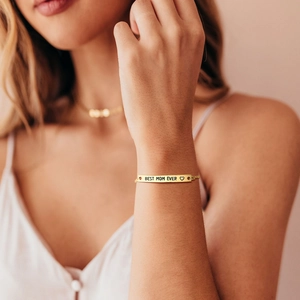 Detailed view of the gold BEST MOM EVER engraved plate on a minimalist chain bracelet