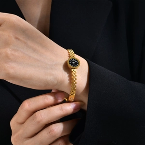 Gros plan d'un bracelet de montre doré avec un mini cadran noir et des chiffres romains