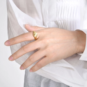 Detail of a minimalist gold oval ring featuring a sunburst radial texture on the surface
