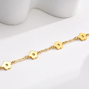 Détail d'un bracelet en acier doré avec des breloques fleurs à cinq pétales