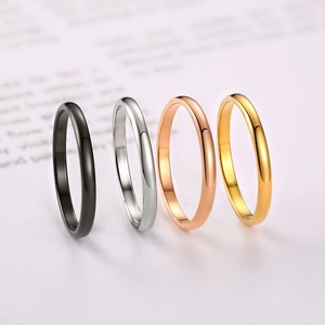 Minimalist stainless steel rings in black, silver, rose gold, and gold on a vintage book
