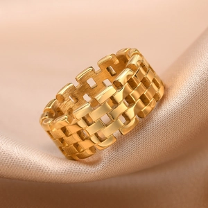 Detail of gold stainless steel mesh ring with woven texture on champagne silk background