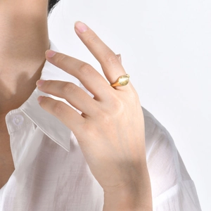 Detail of gold signet ring with sunburst oval face worn on a model's index finger