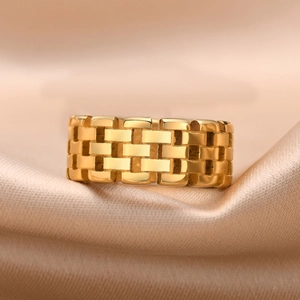 Macro shot of gold stainless steel watchband style ring on elegant silk fabric