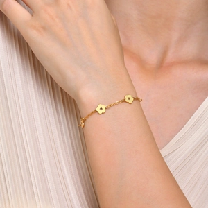 Bracelet en acier inoxydable doré avec breloques de fleurs porté par un mannequin