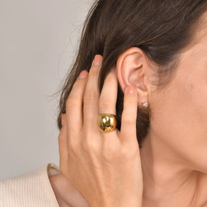 Polished gold curved dome ring and elegant crystal earrings worn by a female model
