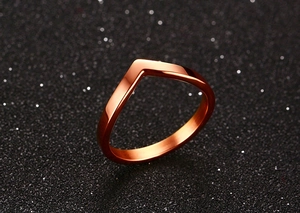 Detailed view of a V-shaped rose gold polished stainless steel ring on a black background