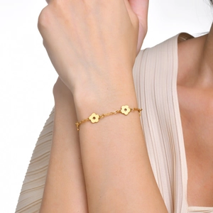 Gros plan d'un bracelet fleur en acier inoxydable doré avec des breloques florales évidées