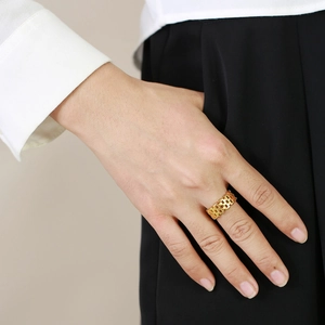 Modern gold-tone mesh strap ring with geometric lattice design on a model's finger
