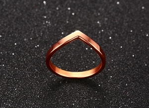 Macro shot of polished rose gold V-shaped titanium steel ring on black glitter surface