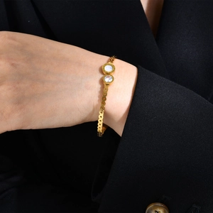 Détail d'un bracelet doré avec gravures de chiffres romains et incrustation de zircon