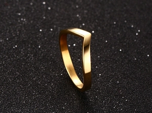 Polished gold V-shaped titanium steel ring on black glitter background detail
