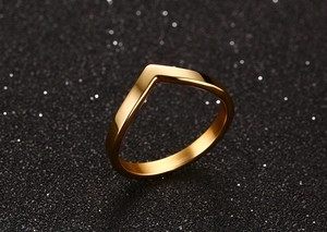 Macro shot of minimalist V-shaped gold ring with polished surface and bokeh background