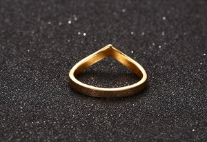 Macro view of a polished gold V-shaped minimalist ring on a textured dark surface