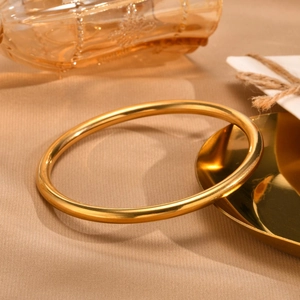 Close-up of a polished gold titanium steel bangle on a luxury warm-toned background