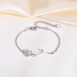 Macro view of silver rose blossom bracelet with intricate hollow petals and heart charm