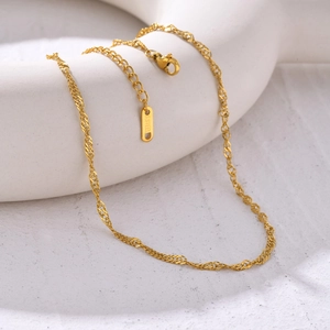 Detailed close-up of golden stainless steel water wave chain with lobster clasp and tag