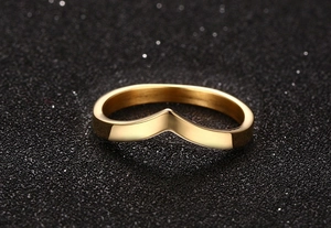 Macro shot of V-shaped golden polished titanium steel ring on black textured background