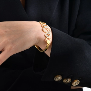 Bracelet à maillons ovales dorés avec pavé de zircons porté sur une manche de costume