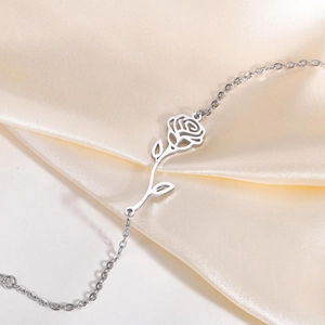 Detailed close-up of a silver hollow rose charm on a delicate stainless steel chain link