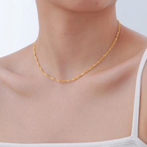 Detailed view of elegant gold water wave chain necklace worn on a model's neck
