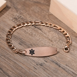 Nahaufnahme des medizinischen ID-Armbands in Roségold mit gravierter Platte auf Holzgrund