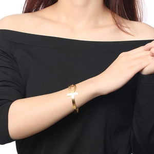 Detail view of gold Ankh cross open bangle bracelet worn on a female wrist