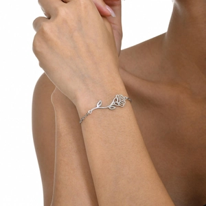 Close-up of a silver stainless steel rose bracelet worn on a woman's wrist with soft lighting