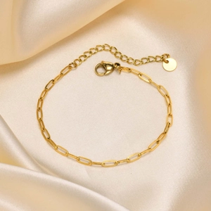 Detail einer goldenen Büroklammer-Kette mit Karabinerverschluss auf Seide