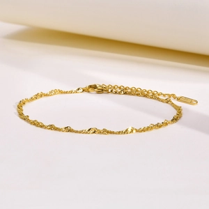 Detail of a shiny gold water wave chain with lobster clasp and extension links