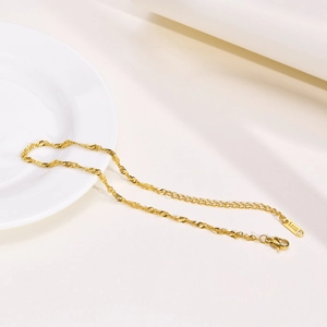 Detail of golden water wave chain with lobster clasp and S. Steel tag on a white plate