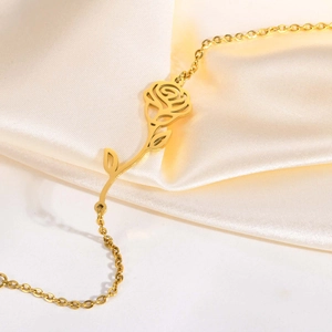 Close-up of golden stainless steel rose flower bracelet on soft yellow silk fabric