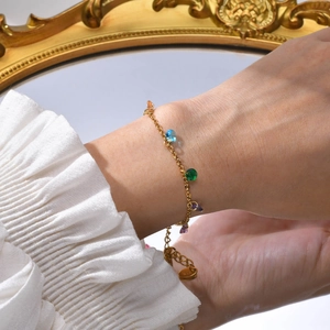 Detail of gold bracelet with colorful zircons on a model's wrist in elegant setting