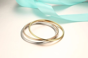 Three minimalist slim metal bangles in gold, silver, and rose gold with polished finish