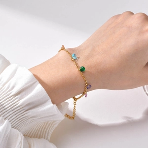 Gold stainless steel chain bracelet with seven colorful zircons on a model's wrist