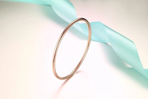 Close-up of minimalist rose gold stainless steel bangle with a polished mirror finish