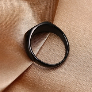 Detailed macro shot of a sleek black dome ring on elegant gold silk fabric texture