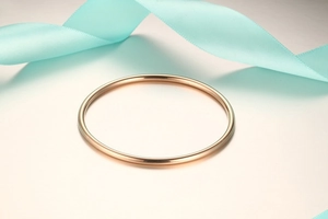 Polished rose gold stainless steel bangle with a minimalist mirror finish and sleek design