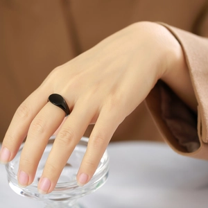 Close-up of a minimalist black oval signet ring with a high-gloss polished metal finish