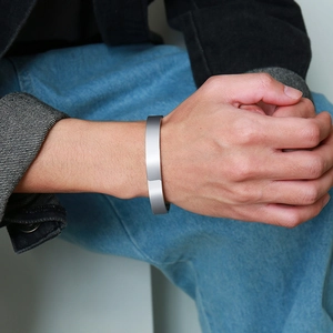 Detail of minimalist stainless steel cuff bracelet with geometric faceted edges on wrist
