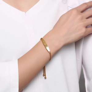 Close-up of a minimalist gold-plated bar bracelet worn on wrist with adjustable pull tie