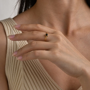 Close-up of a slim 18K gold-plated ring featuring a claw-set round black zircon stone